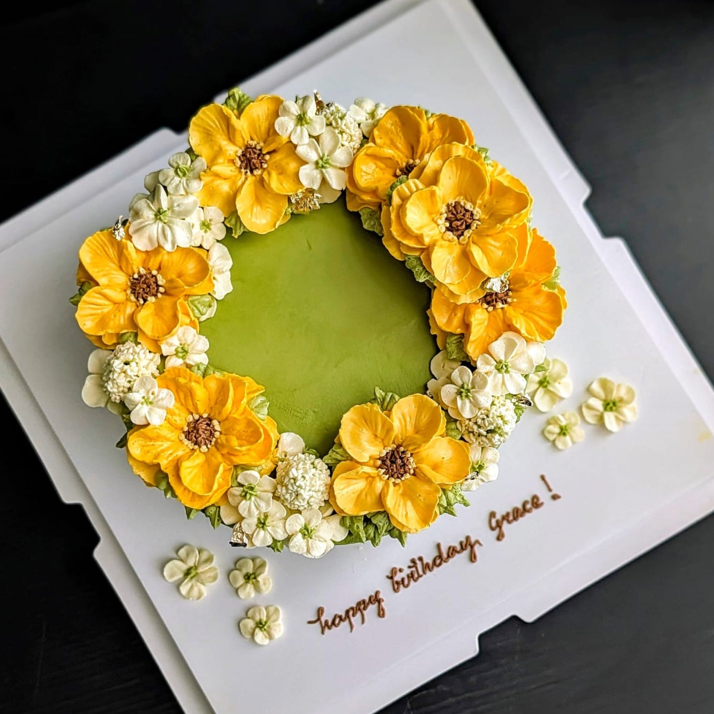 Matcha green birthday cake with hand-piped yellow sunflower and white blossom buttercream wreath, floral wreath cake Singapore