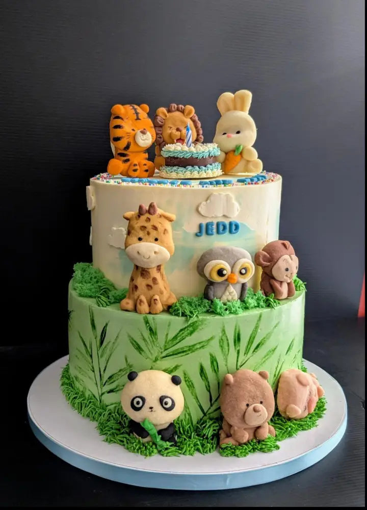 Two-tier jungle animal birthday cake with handcrafted cookie animal toppers including tiger, lion, bunny, giraffe, owl, monkey, panda and bear, custom name cake Singapore