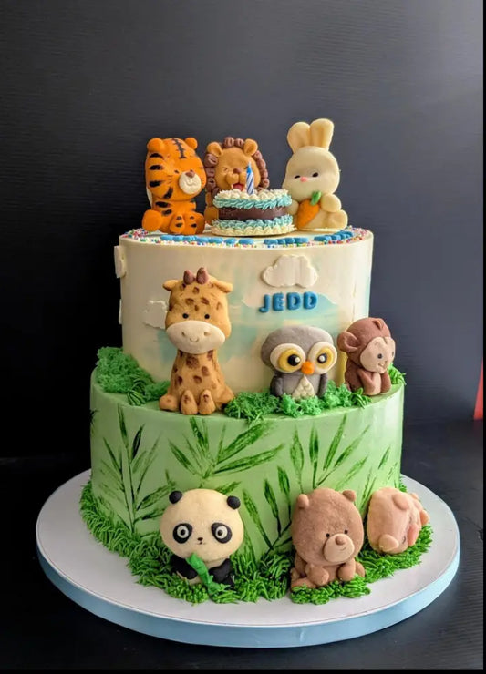 Two-tier jungle animal birthday cake with handcrafted cookie animal toppers including tiger, lion, bunny, giraffe, owl, monkey, panda and bear, custom name cake Singapore