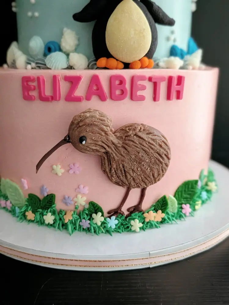 Three-tier birthday cake with turtle, penguin and kiwi bird buttercream decorations in green, blue and pink, custom name cake Singapore
