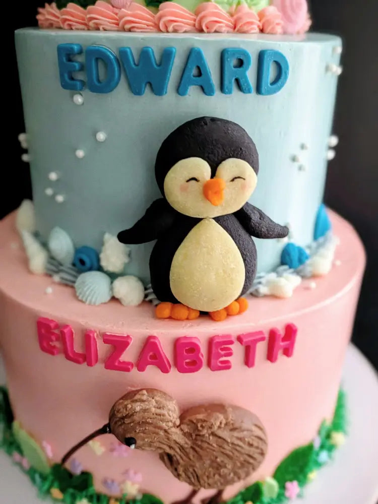 Three-tier birthday cake with turtle, penguin and kiwi bird buttercream decorations in green, blue and pink, custom name cake Singapore