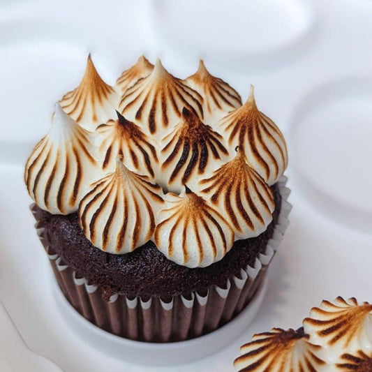 Close-up of a chocolate cupcake topped with golden torched meringue kisses, low sugar healthier dessert Singapore
