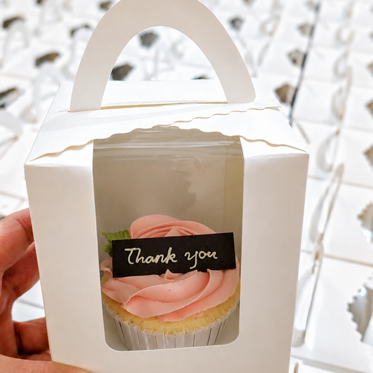 Thank you cupcake with pink rose frosting in white gift box with handle, held by hand