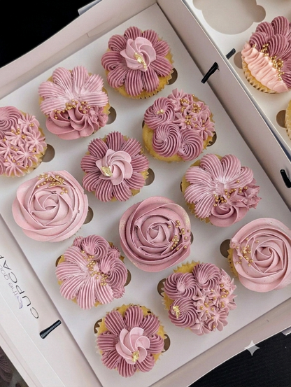 Box of 12 gender reveal cupcakes with hand-piped dusty pink floral buttercream in rose, chrysanthemum and petal fan designs with gold leaf and pearl sprinkles, The Good Cupcakes Singapore