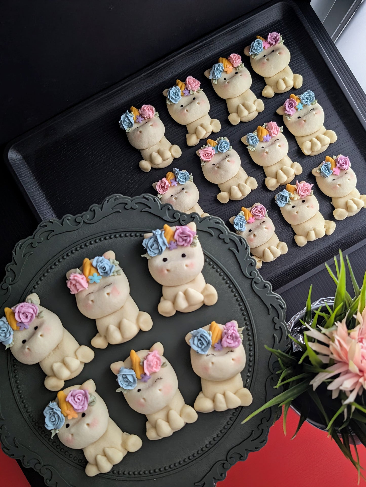 Overhead view of Rainbow Unicorn shortbread cookies on a dark display board with fresh flowers — The Good Cupcakes Singapore