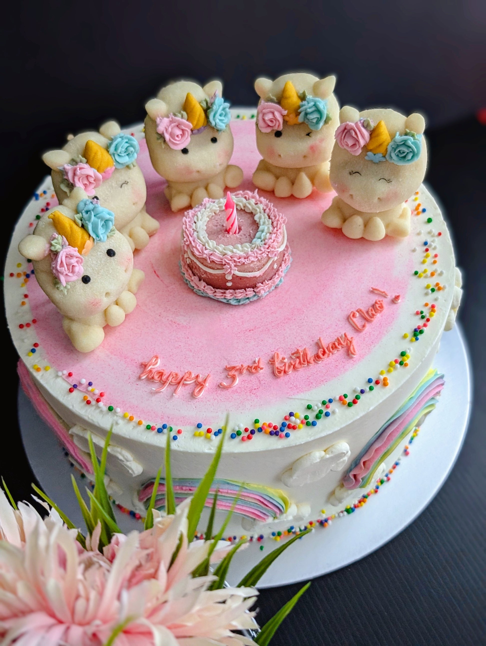 Close view of pastel unicorn birthday cake with hand-sculpted unicorn toppers and floral detail — The Good Cupcakes Singapore