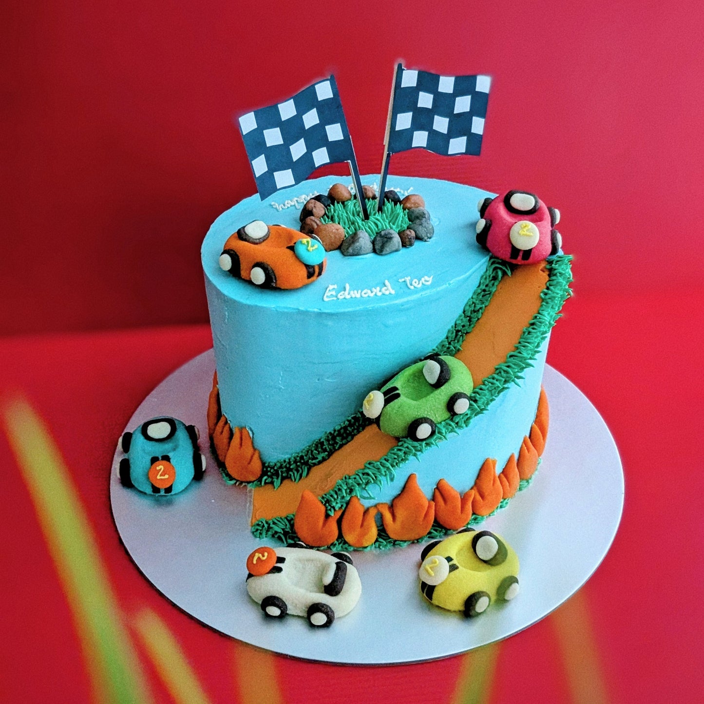 Car-themed birthday cake with baby blue buttercream, toy racing cars and road details, low calorie, no fondant