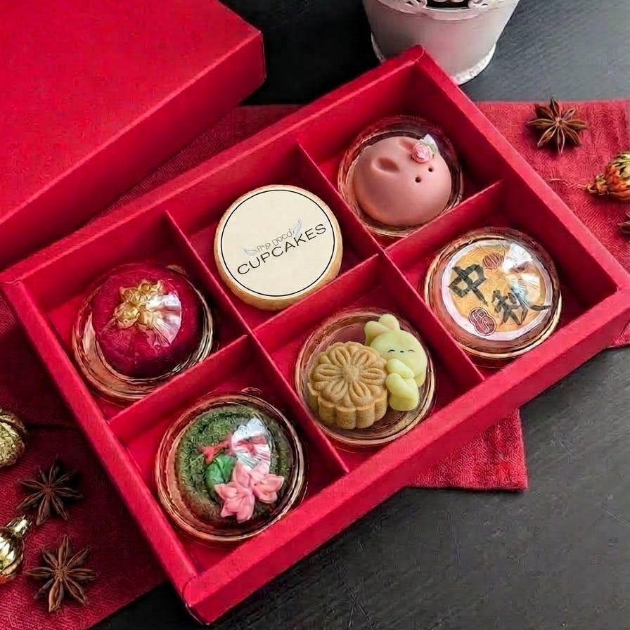 Overhead shot of an open red gift box with six mid-autumn shortbread cookies in individual compartments, styled with dried flowers and star anise.