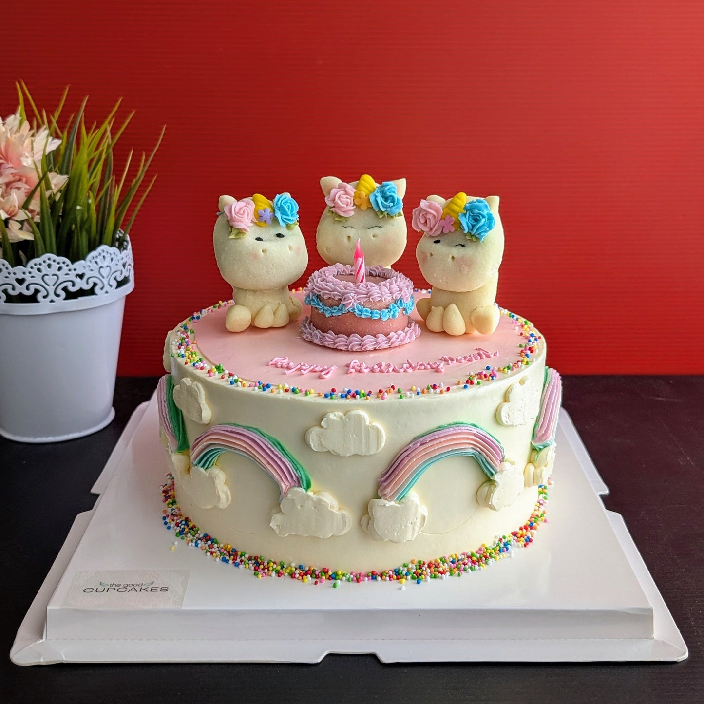Side view of unicorn birthday cake displayed on a stand with rainbow drip, styled with fresh greenery — The Good Cupcakes Singapore