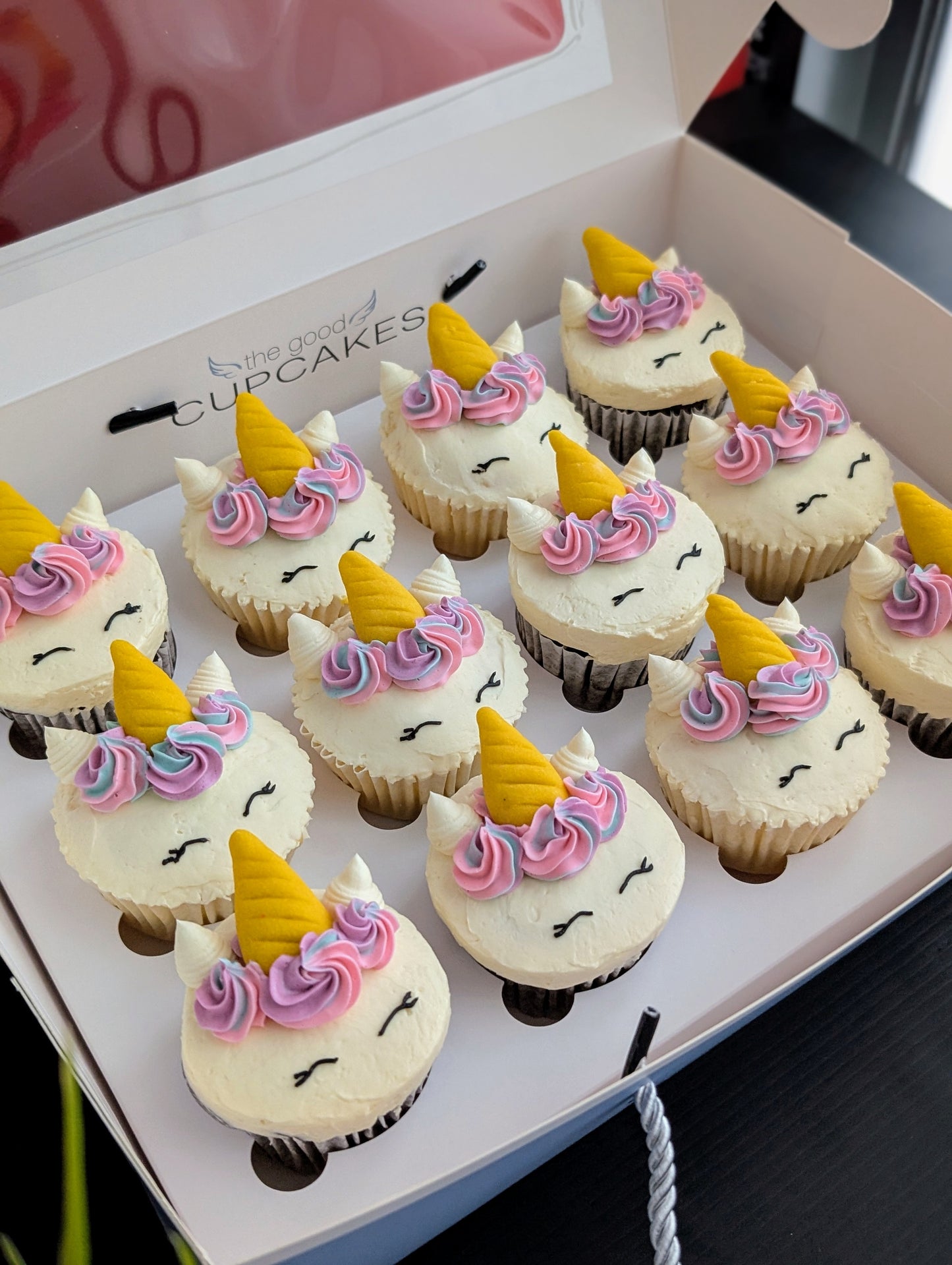Tray of Rainbow Unicorn cupcakes viewed from above, colourful hand-piped buttercream unicorn faces — The Good Cupcakes Singapore