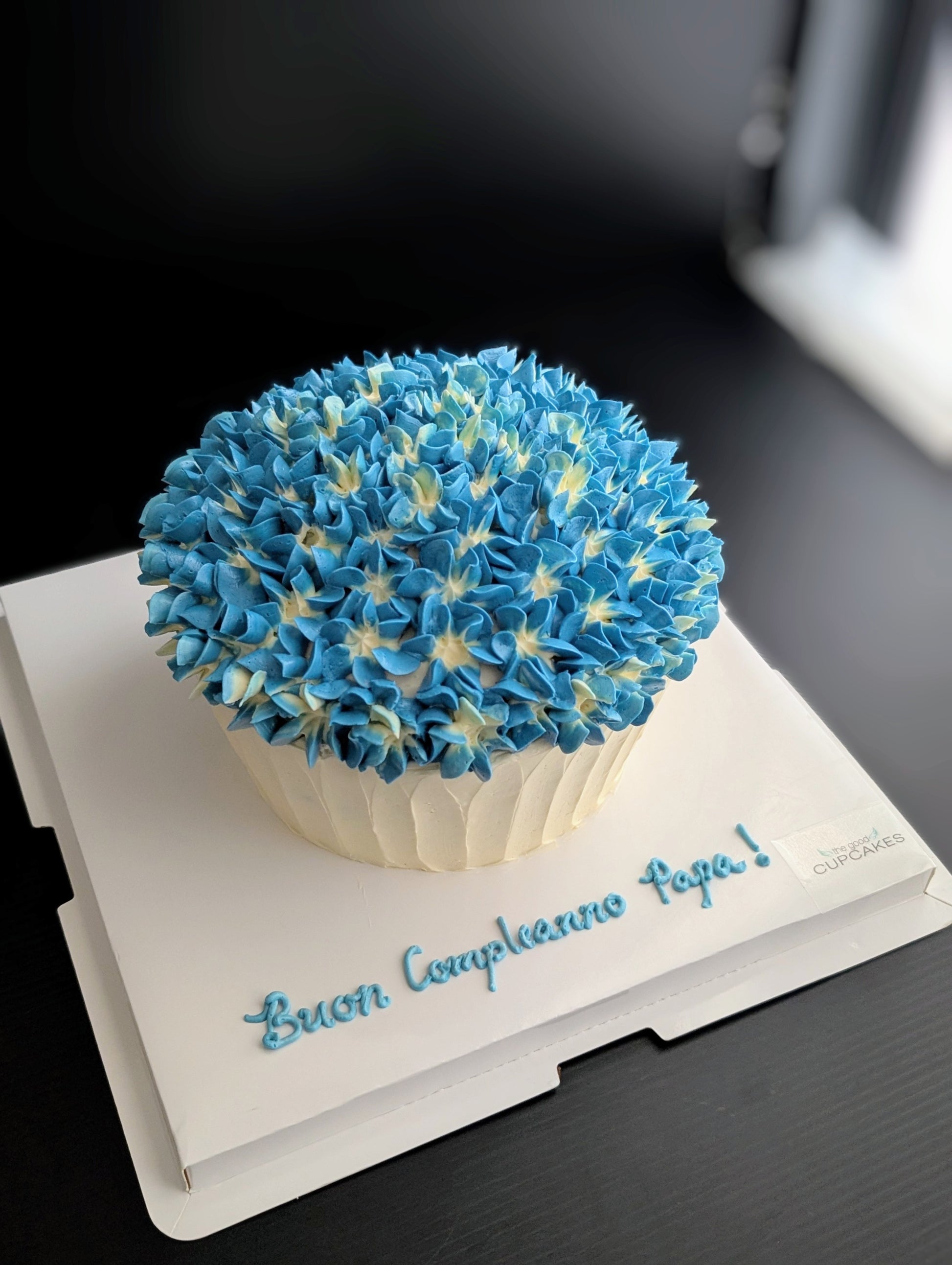 Giant cupcake cake shaped like oversized cupcake with blue hydrangea buttercream top and white ribbed base, low-sugar celebration cake Singapore