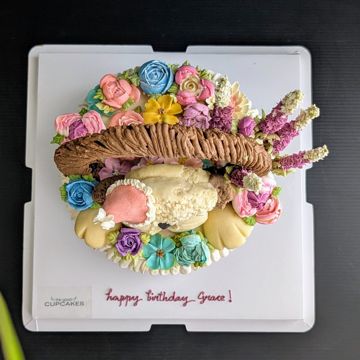 Floral basket cake with a sculpted puppy surrounded by hand-piped purple, pink and yellow flowers healthy low-sugar birthday cake