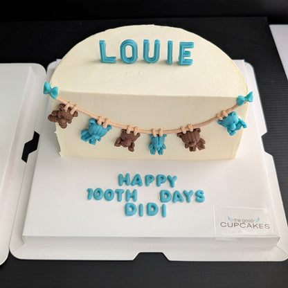 100-day baby celebration cake with cream buttercream, hand-piped teddy bear bunting in teal and brown, custom name topper, low-sugar Singapore