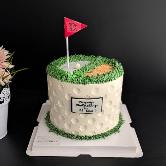 Golf course birthday cake with white dimple texture, green piped grass, sand bunker, golf ball and pink flag topper, custom men's cake Singapore