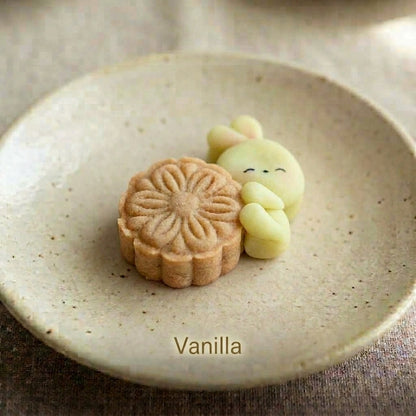 Vanilla shortbread cookie with a hand-piped bunny design, whole, on a speckled ceramic plate.