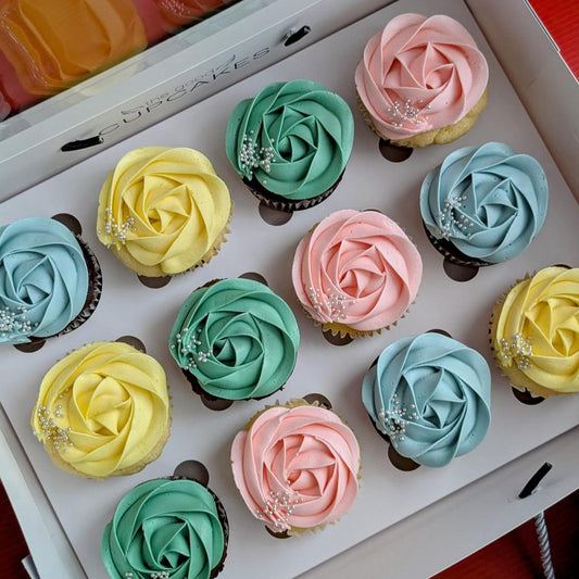 Box of 12 chocolate cupcakes with pastel rose-piped buttercream in pink, blue, green and yellow with silver pearl sprinkles, The Good Cupcakes Singapore
