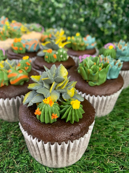 Pair of succulent floral cupcakes on grass surface, detailed blue, green and yellow buttercream flower piping — The Good Cupcakes Singapore