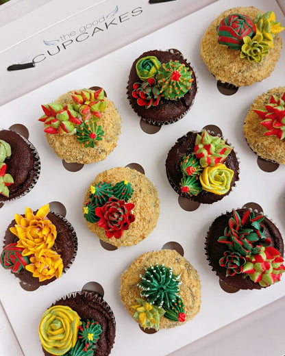 Close overhead shot of succulent floral cupcakes in gift box lid, green cactus and orange flower buttercream detail — The Good Cupcakes Singapore