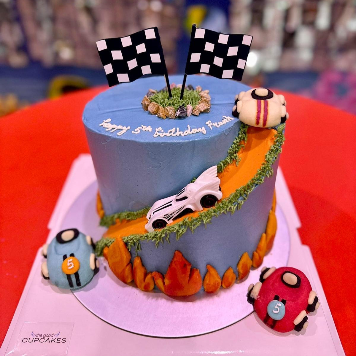 Car-themed birthday cake with baby blue buttercream, toy racing cars and road details, low calorie, no fondant