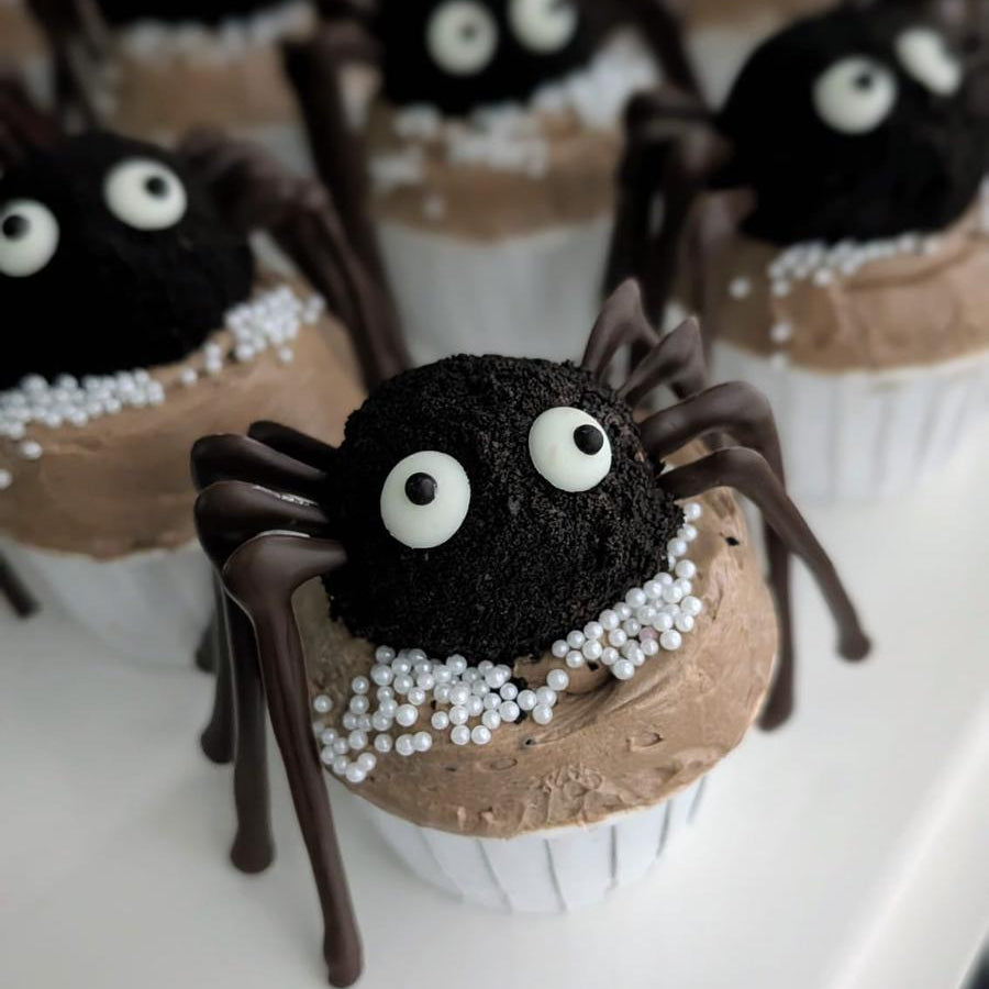 Spider cupcakes with chocolate cake ball spider topper, googly eyes, chocolate legs, and caramel buttercream with white pearl sprinkles, low-sugar Halloween cupcakes Singapore