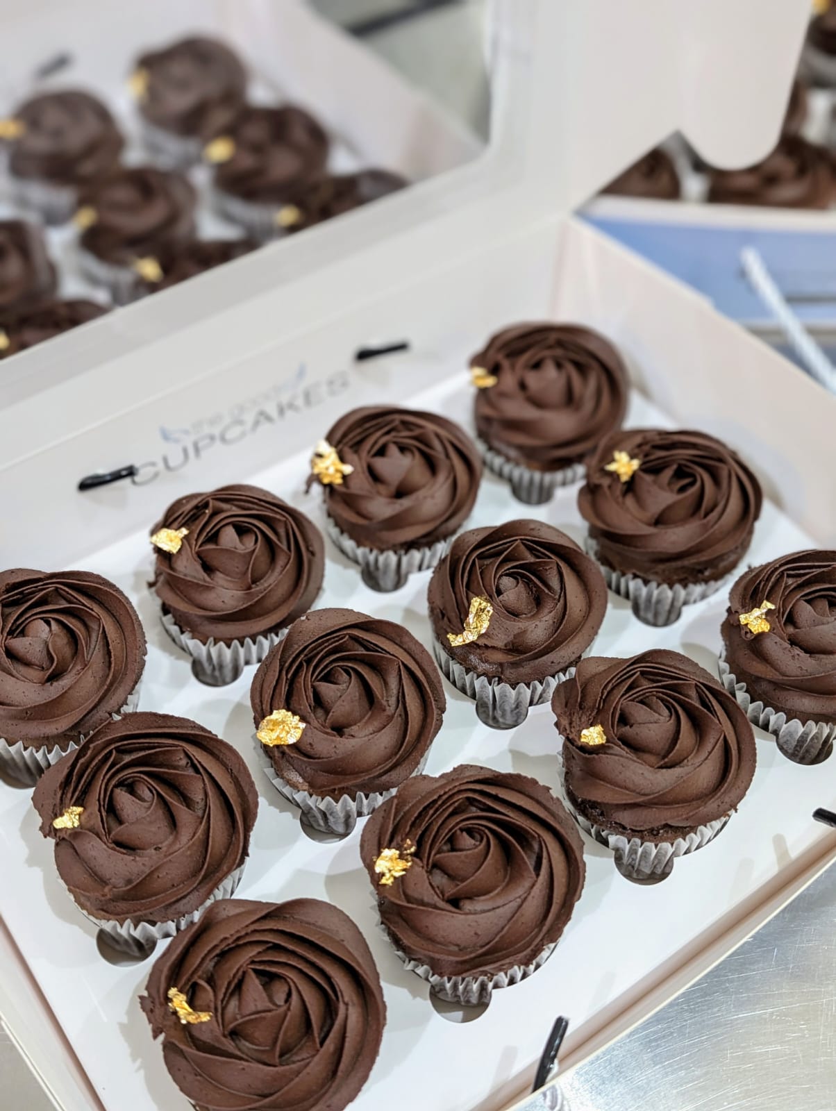 Box of 12 chocolate cupcakes with rose-piped dark chocolate buttercream and edible gold leaf, low sugar healthier dessert
