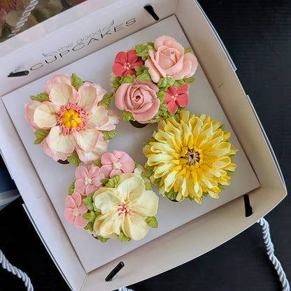 Four handcrafted floral buttercream cupcakes in a The Good Cupcakes gift box — featuring a peony, rose, chrysanthemum and magnolia in pink, yellow and cream