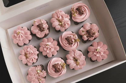 Box of 12 gender reveal cupcakes with hand-piped pink buttercream florals, teddy bear toppers and gold leaf, The Good Cupcakes Singapore
