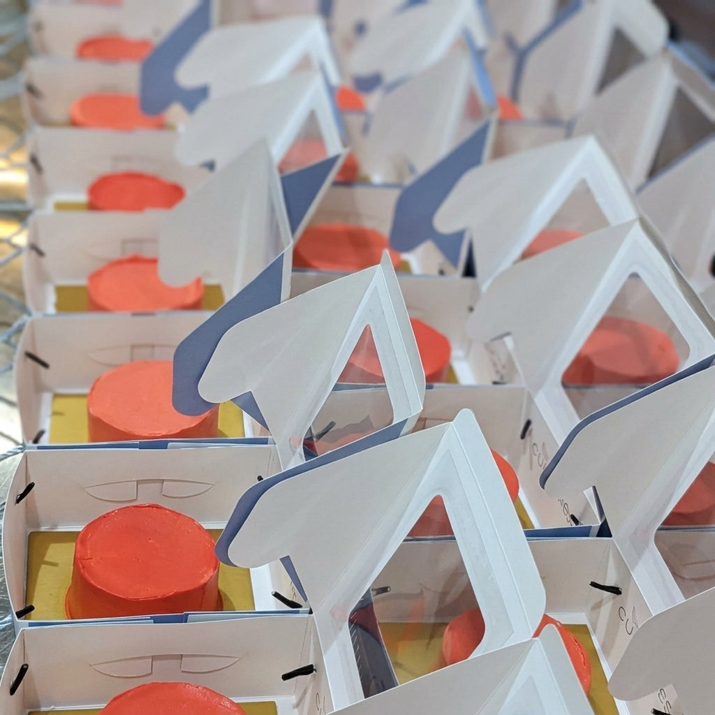 Rows of red-frosted individual cakes prepared in open boxes for a corporate decorating workshop
